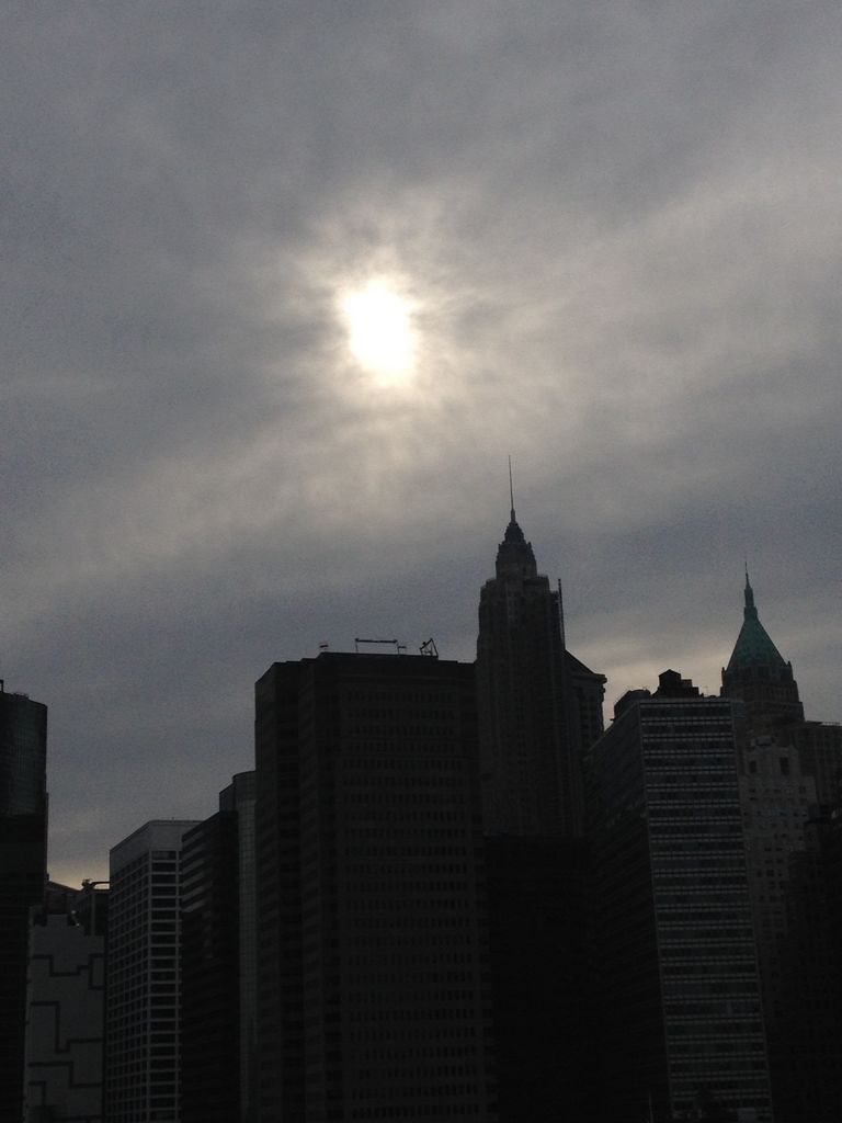 A hazy sun obscures the down town Manhattan sky scape