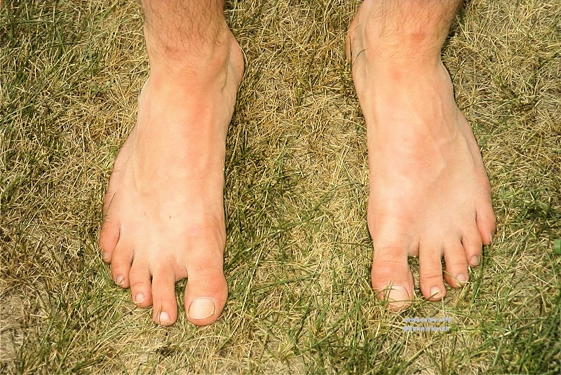 Bare man's feet on and barefeet on lawn