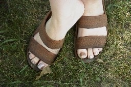 Womens Feet in sandals on a grass lawn